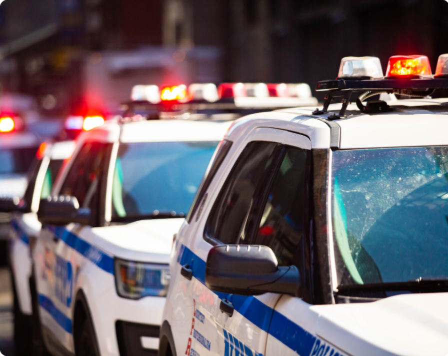 Multiple police vehicles with flashing red and white lights parked in a line