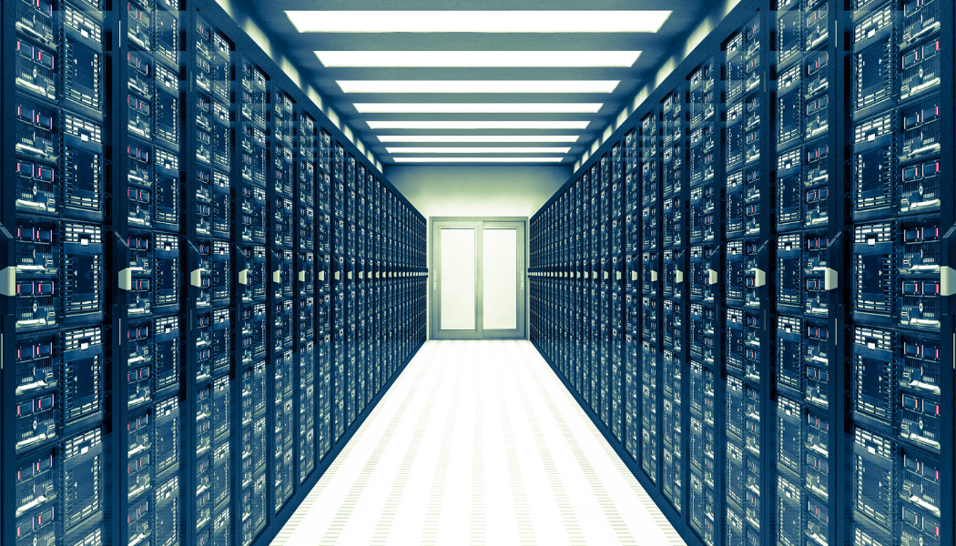 A data center corridor with rows of server racks on both sides and a door at the end.