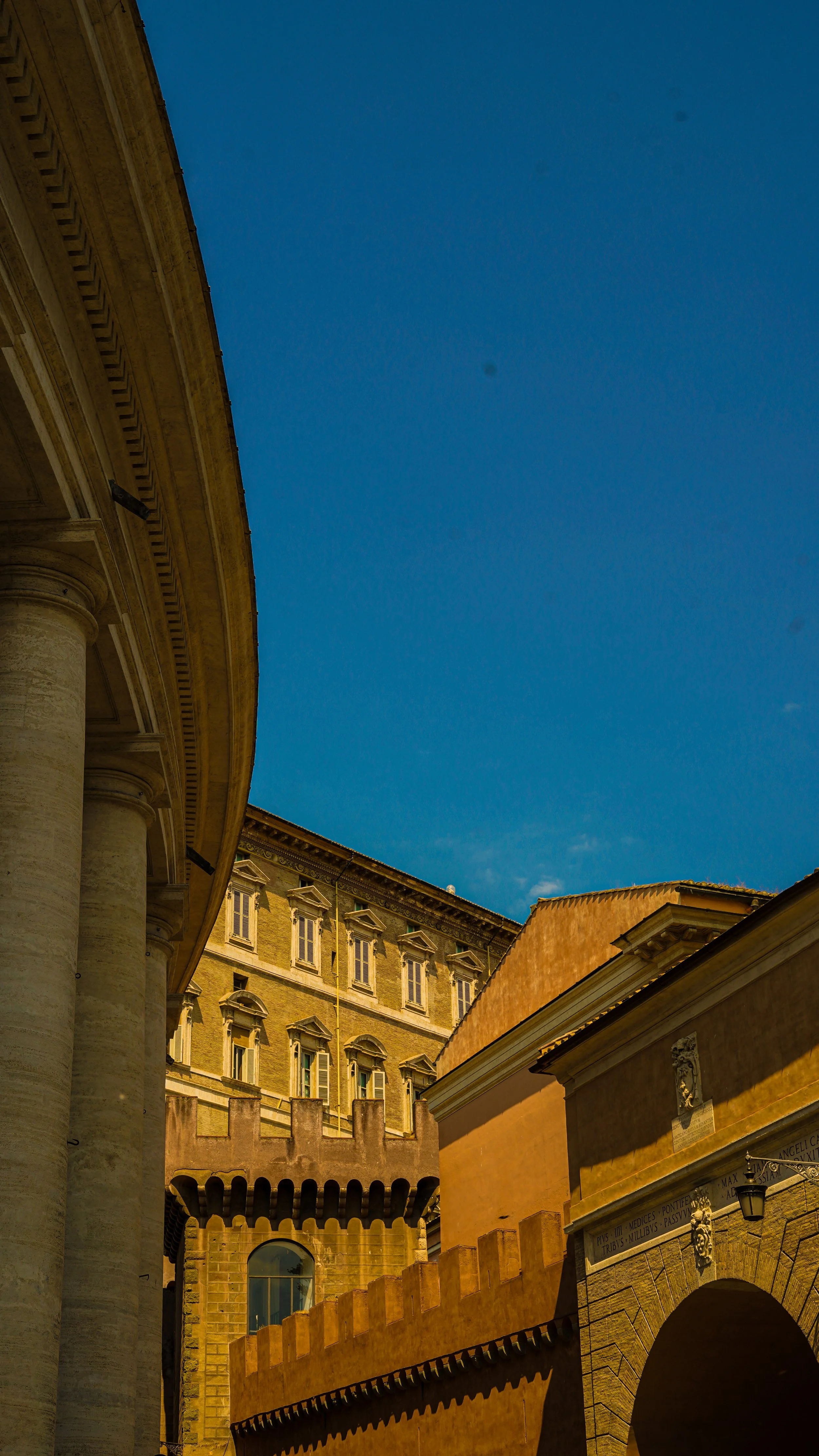 View of historic European buildings with columns and ornate architecture under a clear blue sky.