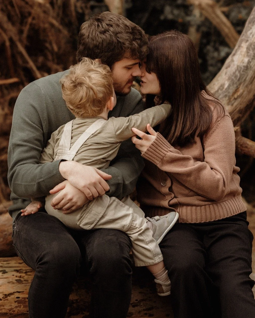 Family with child having a cuddle while on a family photography session in the woods.