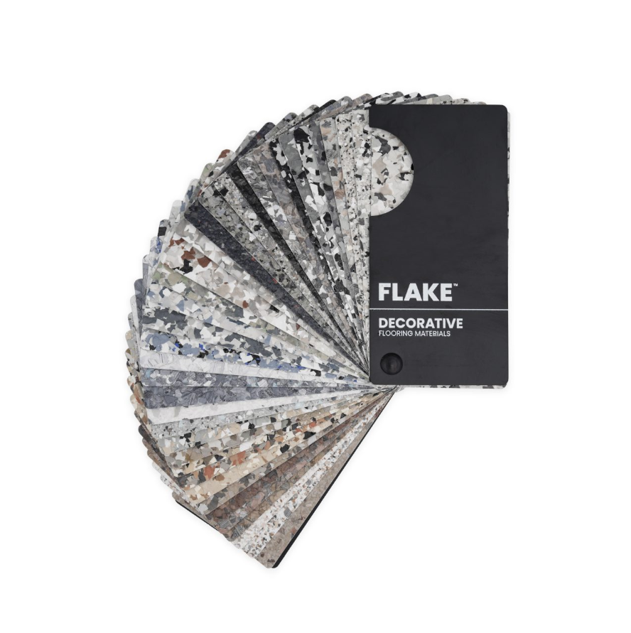A fan deck of decorative flooring samples in various gray, black, white, and brown patterns, with a black sample card labeled 'FLAKE' and 'DECORATIVE FLOORING MATERIALS'.