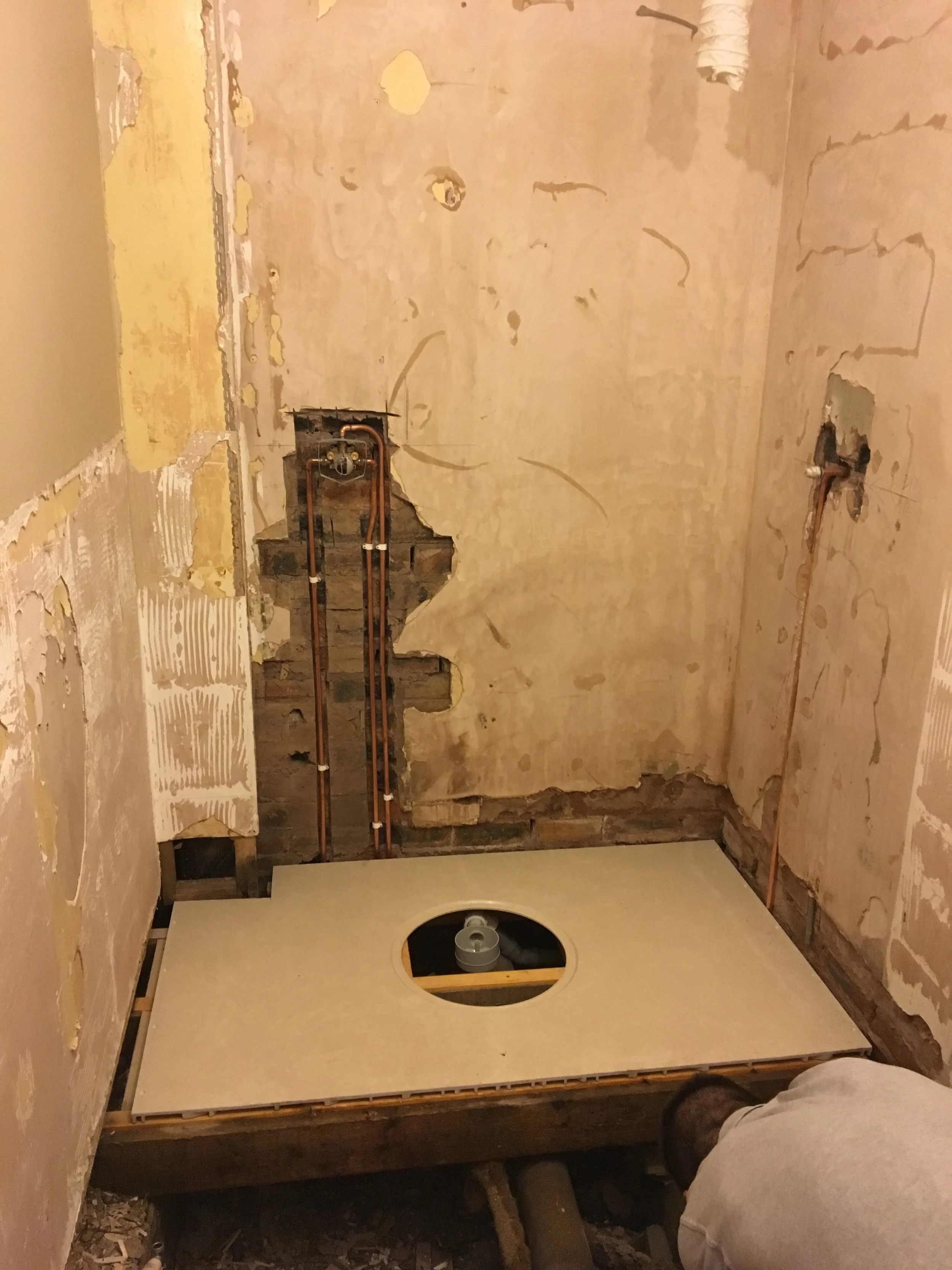 Bathroom renovation in progress with exposed walls, plumbing, and a new toilet flange installation.