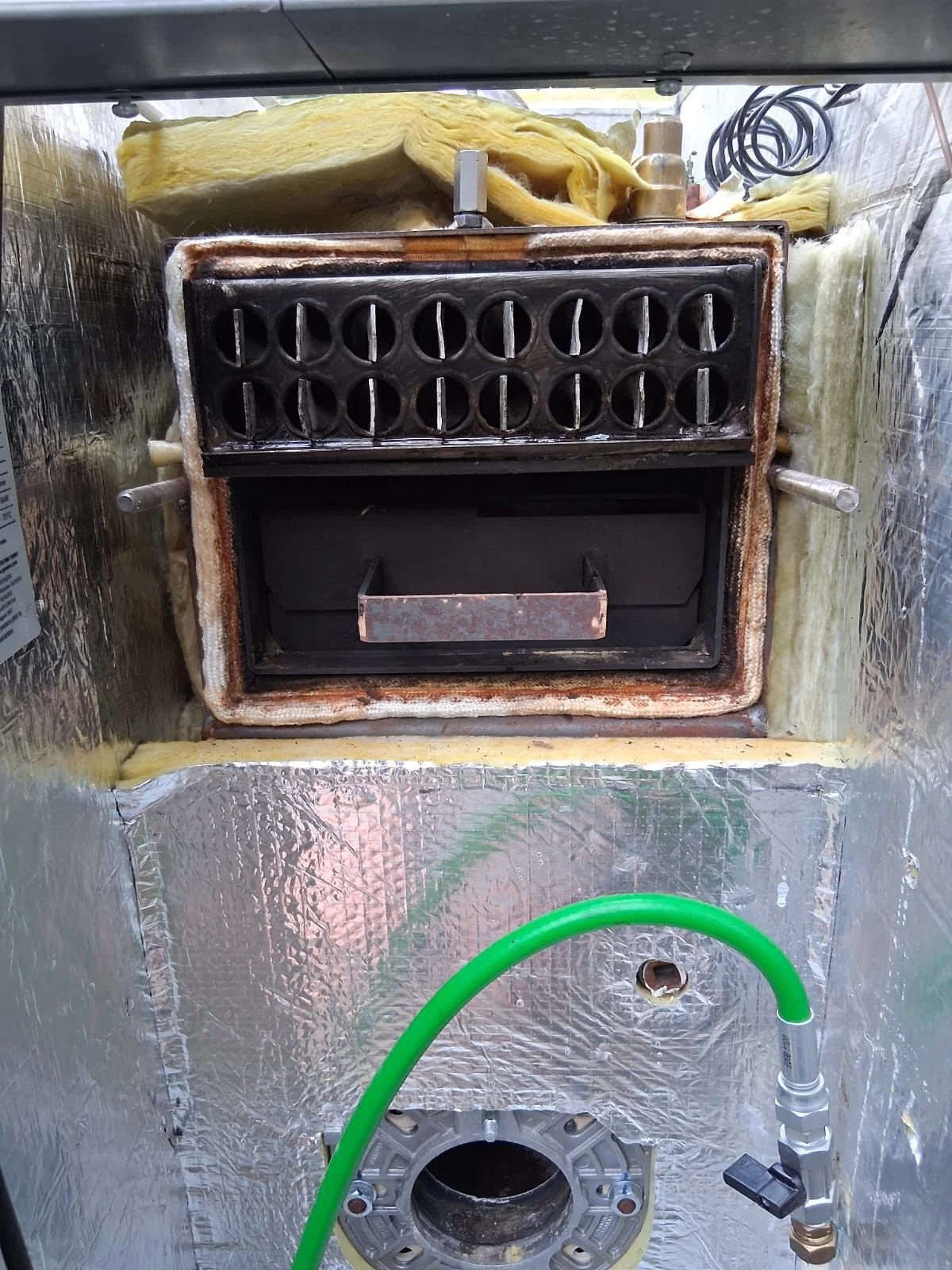 Inside of a modified or disassembled oven or kiln with insulation and metal components visible.