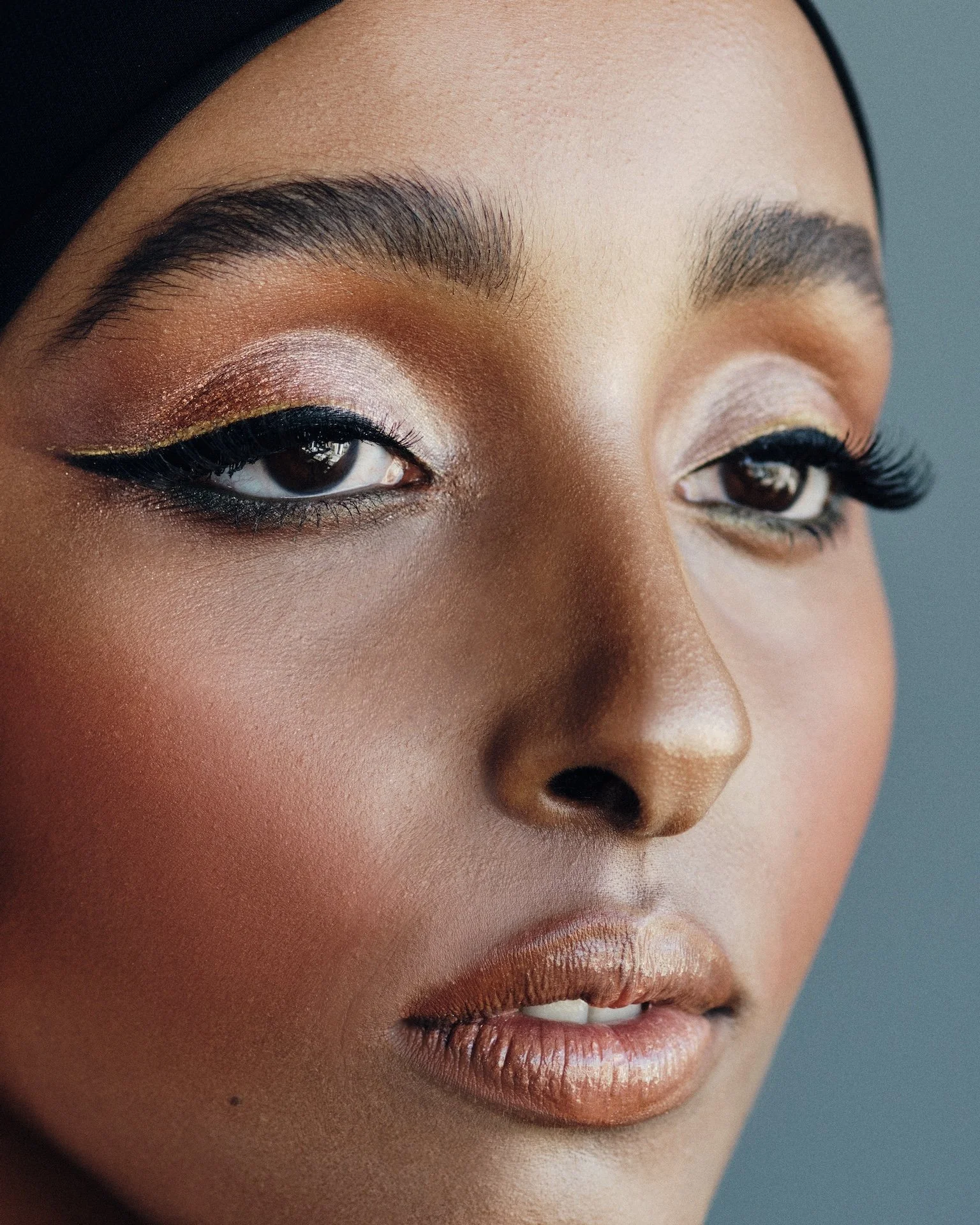 Close-up of a woman's face with makeup, focusing on eye makeup, lips, and smooth skin.