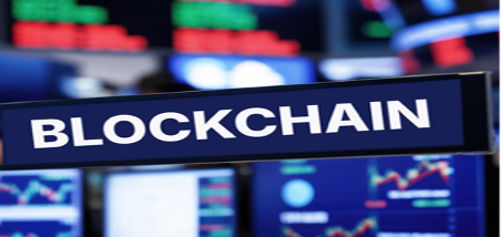 Close-up of a sign reading 'BLOCKCHAIN' with digital screens with graphs in the background.