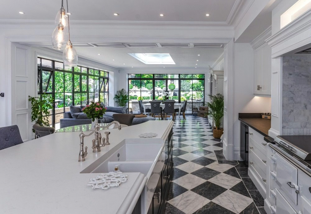 Bright open-concept kitchen and living area with black and white checkered flooring, large windows, and modern decor.