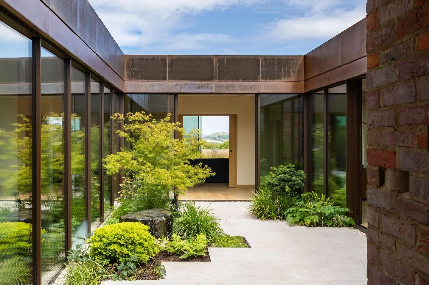 Modern interior with large glass windows, greenery, and a view of the outdoors.