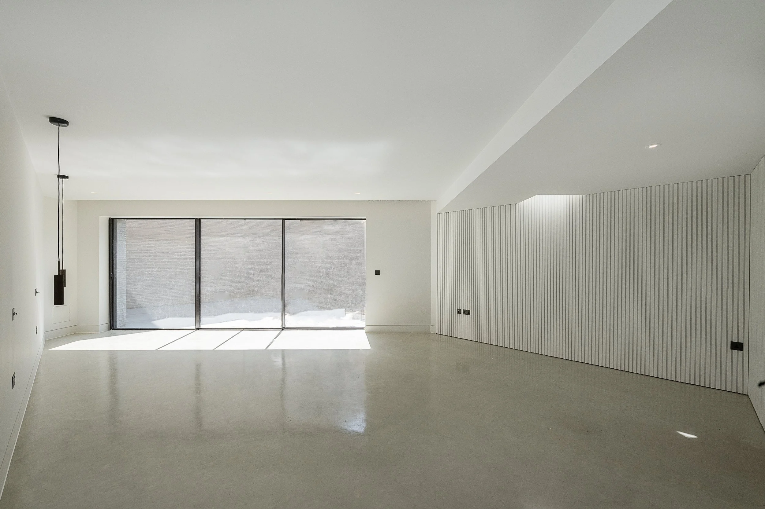 Empty modern room with white walls, minimalist design, large windows with snow outside, and a striped wall panel.