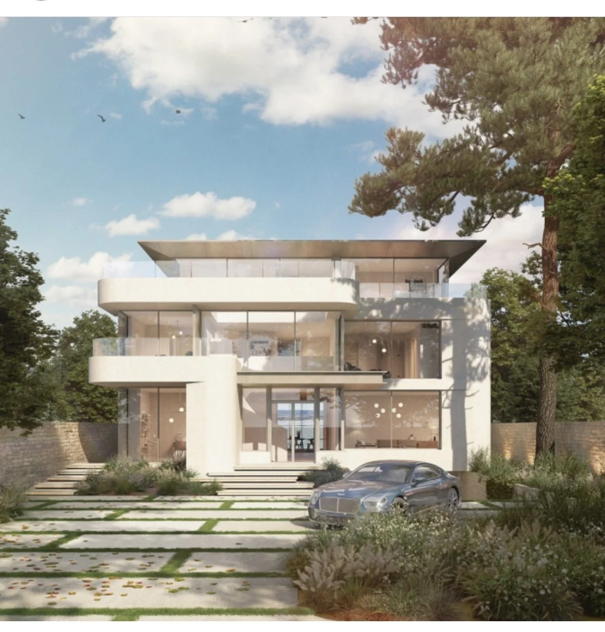 Modern multi-story house with large glass windows and balconies, surrounded by greenery, with a silver car parked in front and a landscaped pathway.