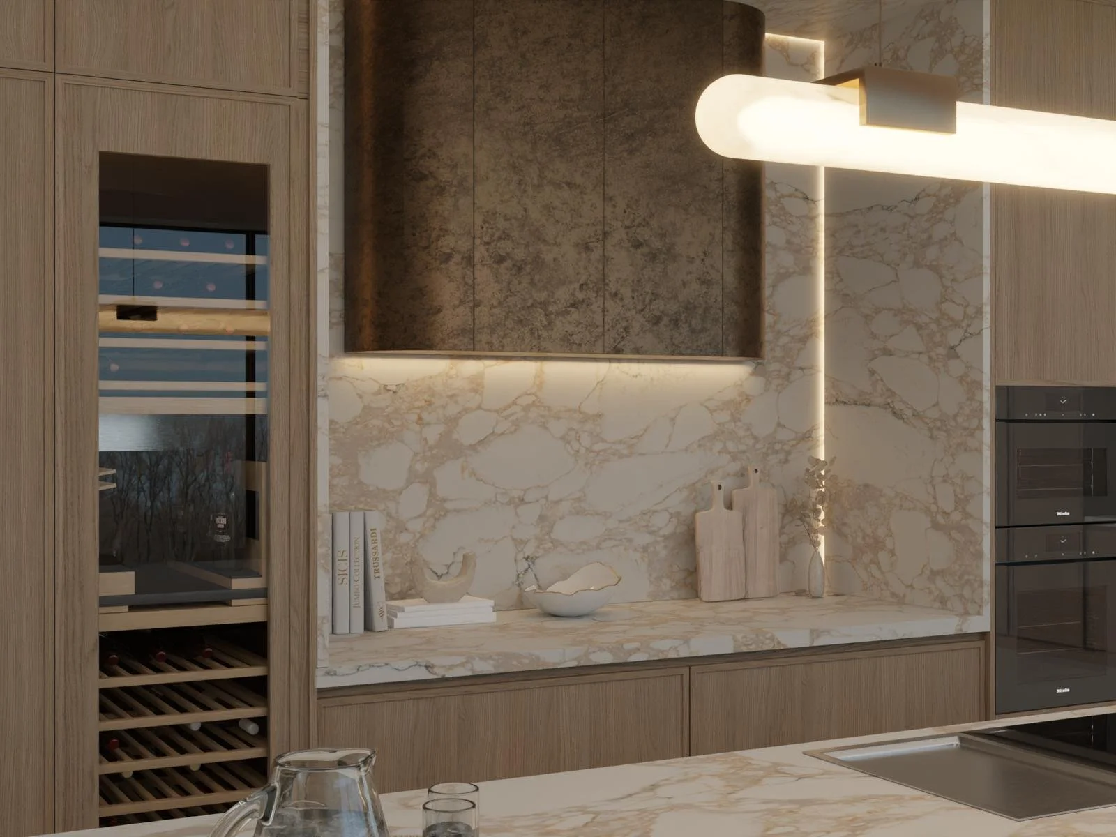 Modern kitchen with beige marble countertops and backsplash, wooden cabinetry, and built-in appliances. Decorative items include books, vases, and a bowl on the counter.