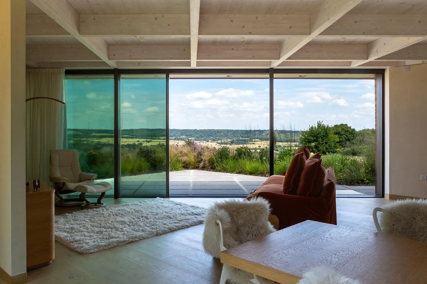 Living room with large glass sliding doors showing a scenic outdoor view of fields and trees.