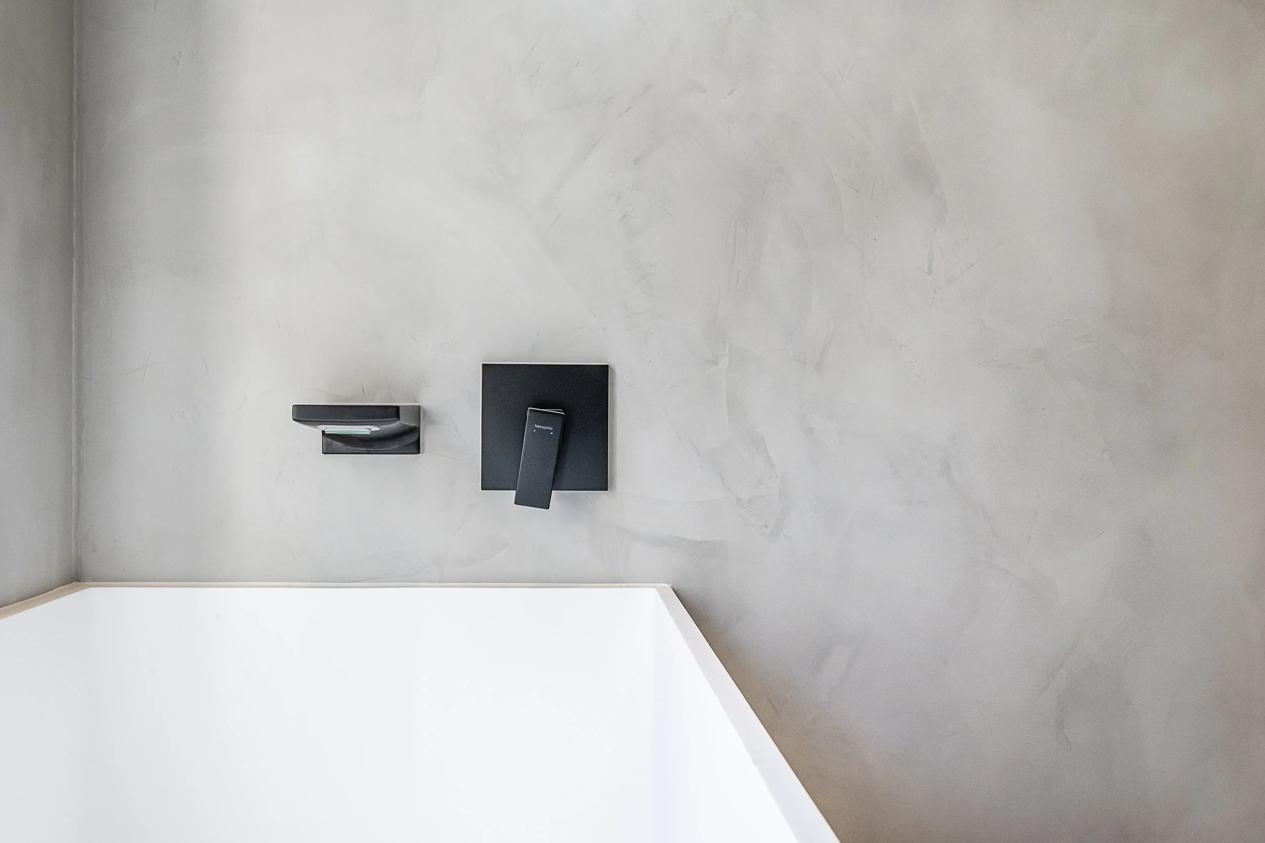 Close-up of a modern black door lock and handle on a gray textured wall near the ceiling.