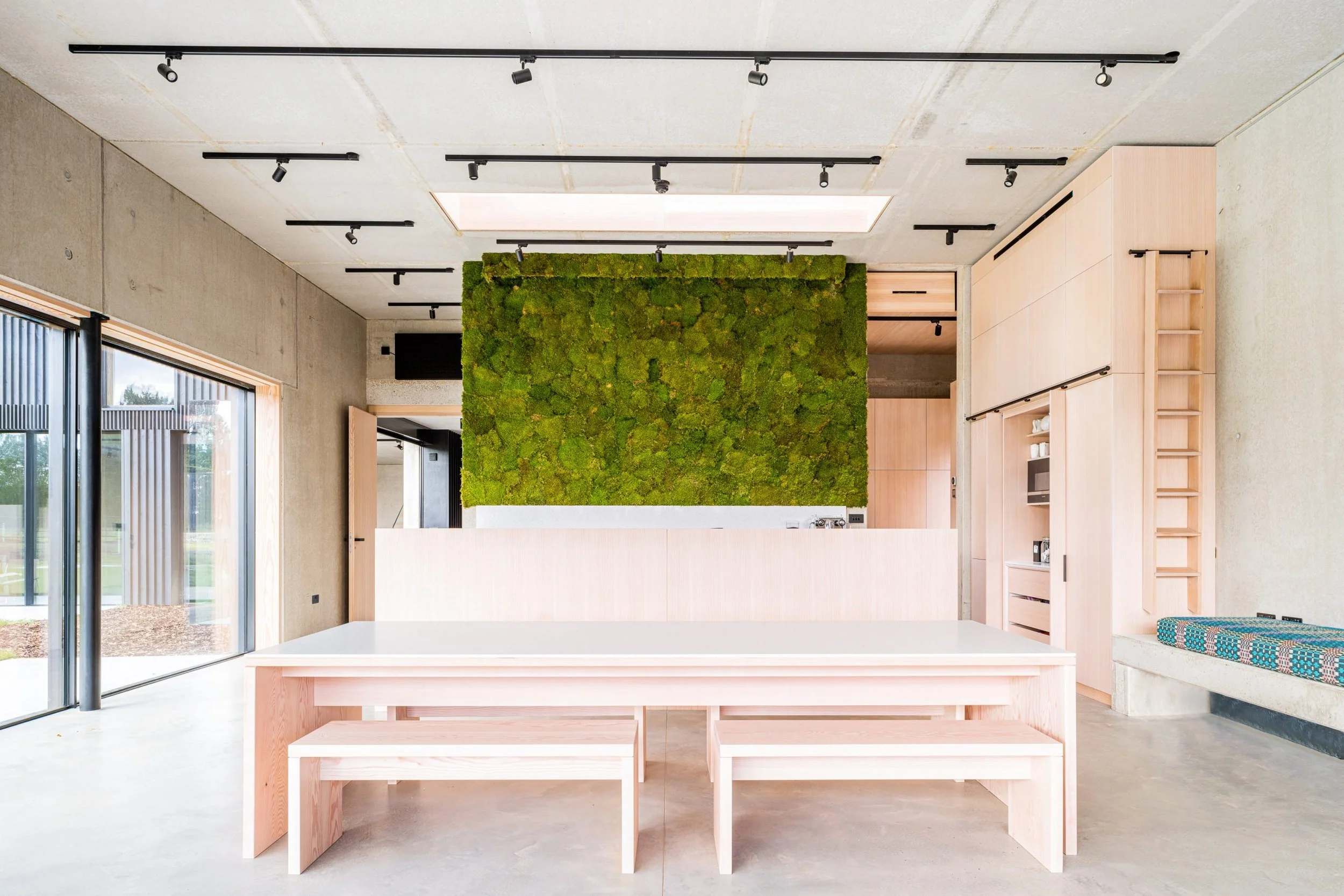 Modern interior with light wood furniture, moss wall accent, and large windows.