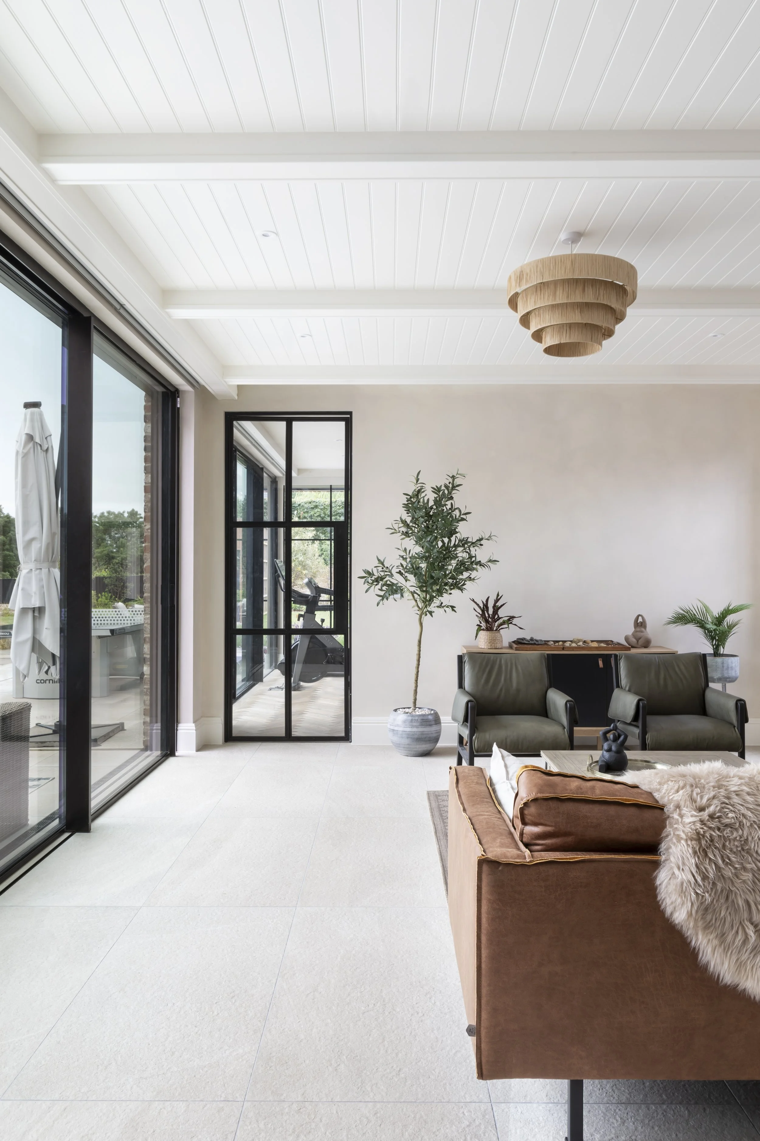 Modern living room with sliding glass doors, potted plants, and minimalist decor.