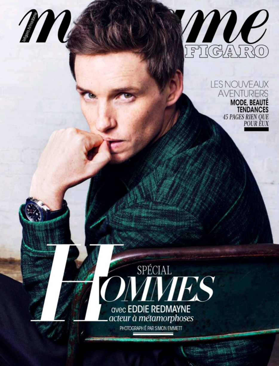 Cover of Madame Figaro magazine featuring Eddie Redmayne, wearing a green patterned jacket, seated with his left hand near his mouth, looking directly at the camera.