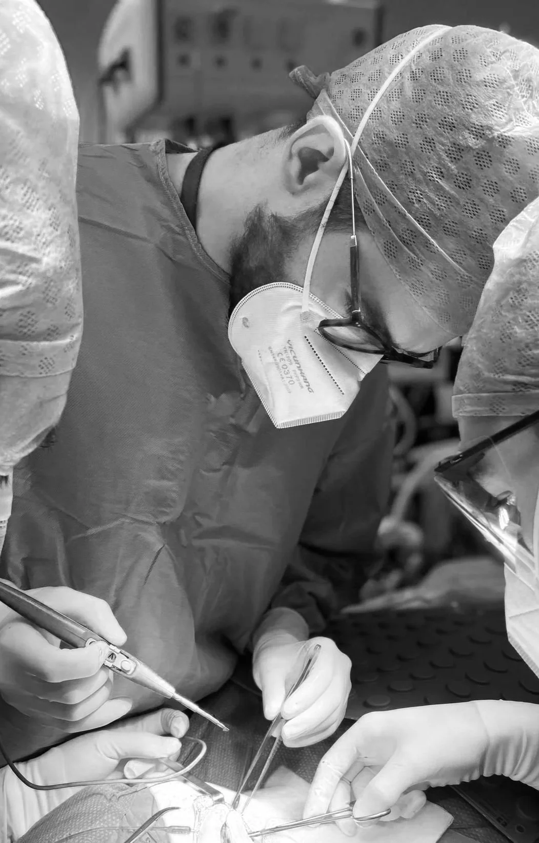 Medici in sala operatoria che eseguono un'operazione chirurgica, indossando camici, mascherine, cappelli e guanti.