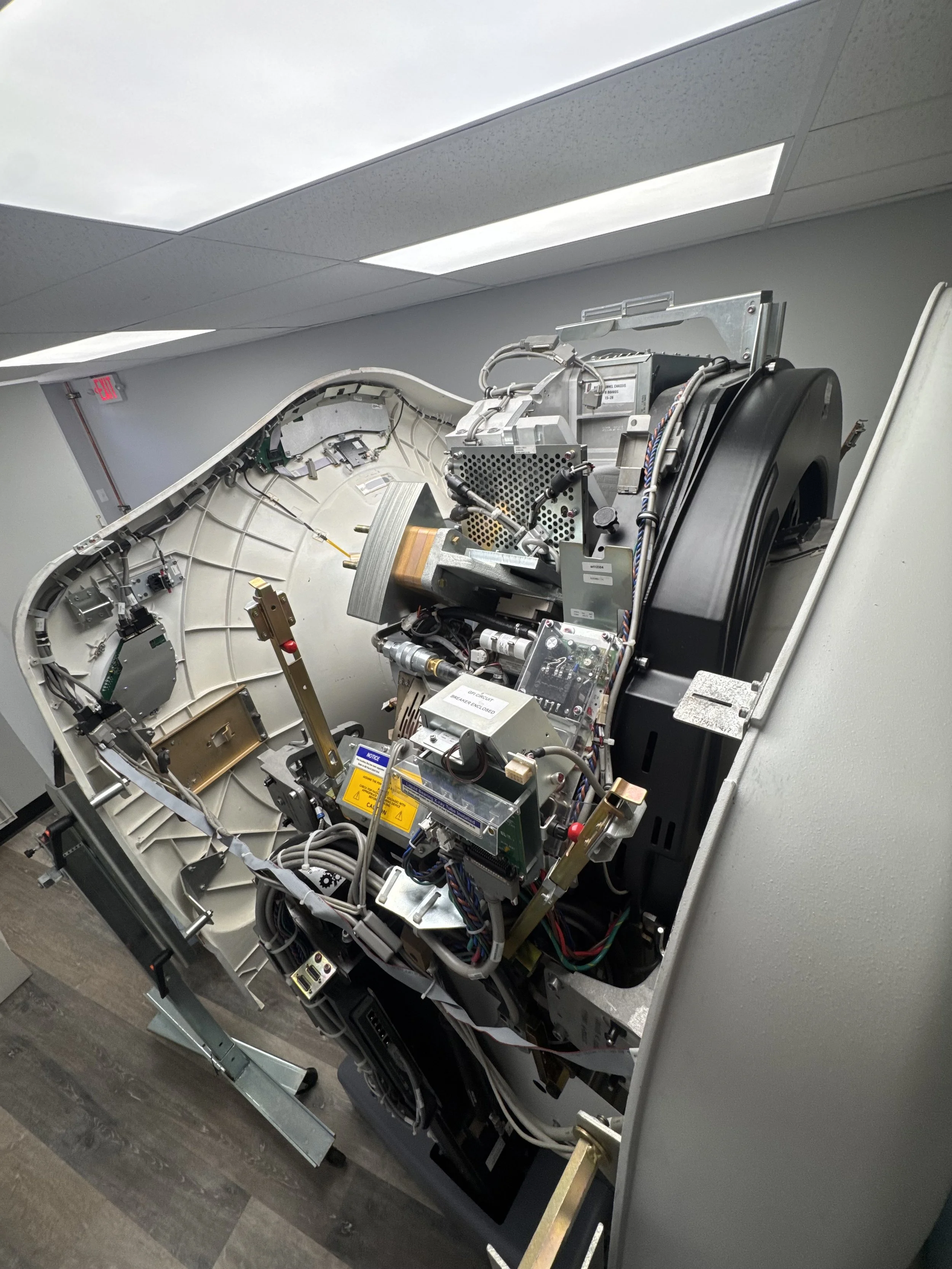Internals of a CT scanner showing various electronic components, wires, and mechanisms.