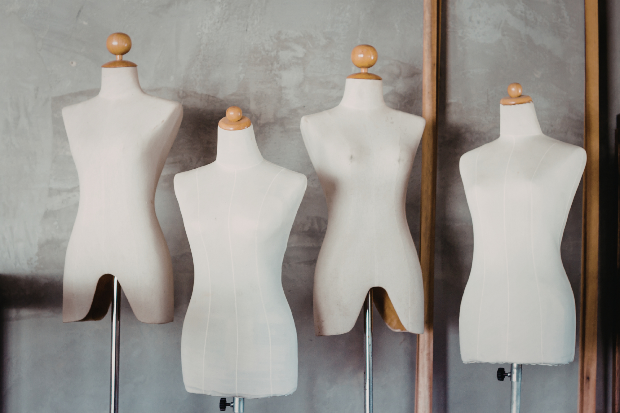 four mannequins with wooden tops against a concreate wall