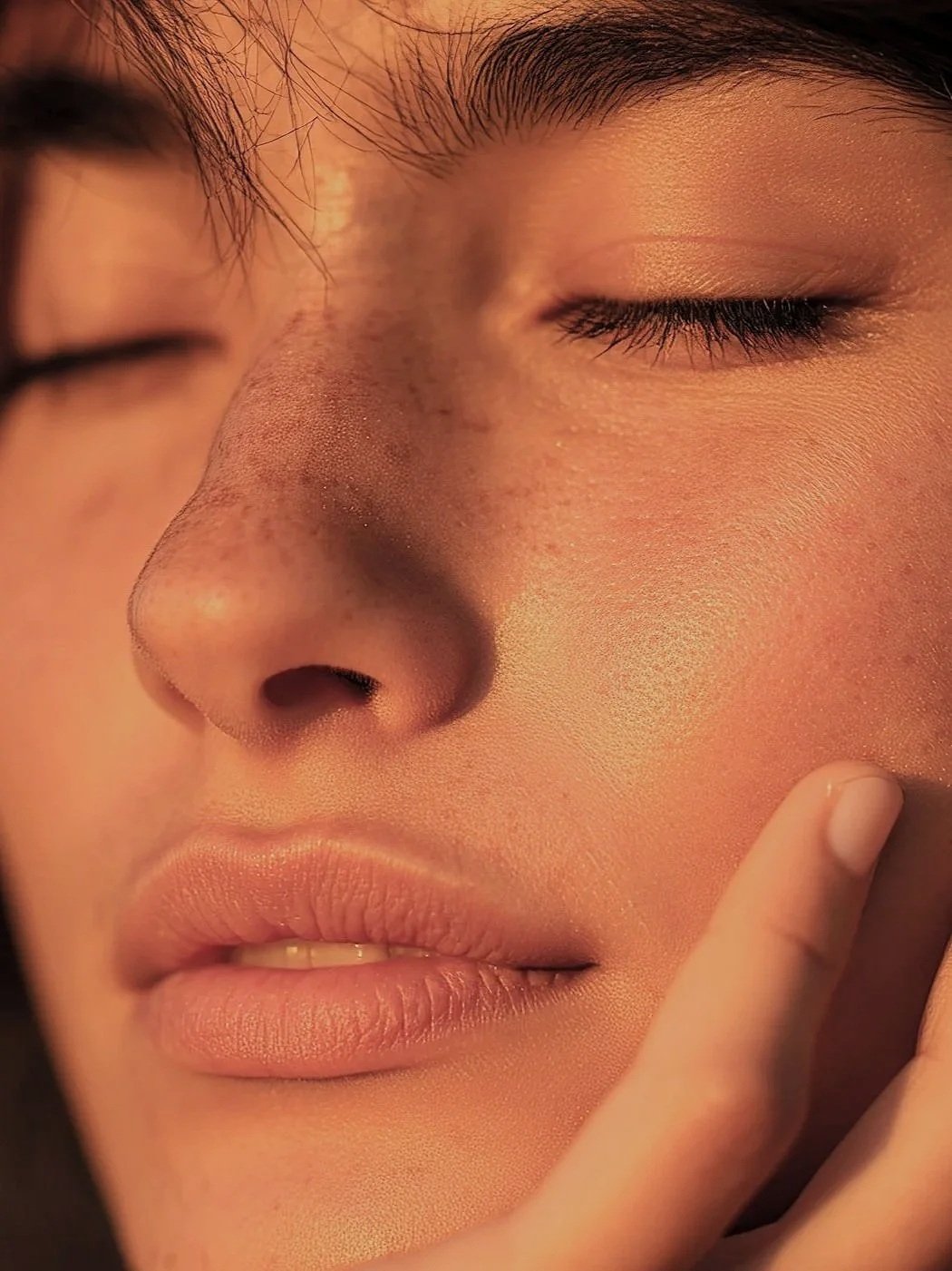 Primer plano de un rostro humano con ojos cerrados, piel detallada y expresión tranquila.