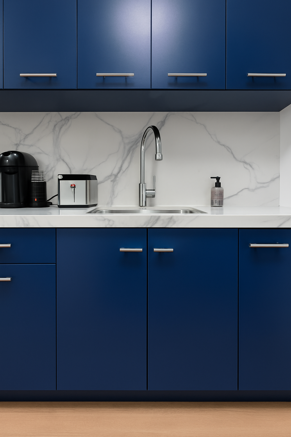 Kitchen with blue cabinets, stainless steel faucet, white marble backsplash, and small appliances including a coffee maker, toaster, and soap dispenser.