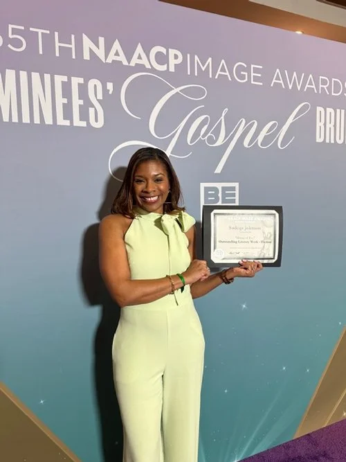 A woman holding a framed certificate at the 55th NAACP Image Awards, standing in front of a backdrop with the words 'Gospel' and 'Ministries'.