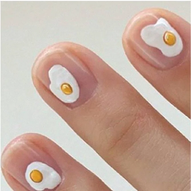 Fingers with nail art designed to look like sunny side up eggs.