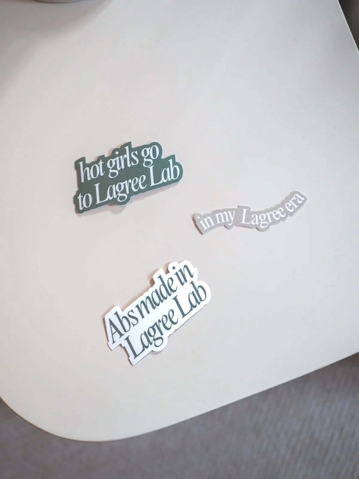 Decorative stickers on a wall with phrases: "hot girls go to Lagree Lab," "in my Lagree era," and "Abs made in Lagree Lab."