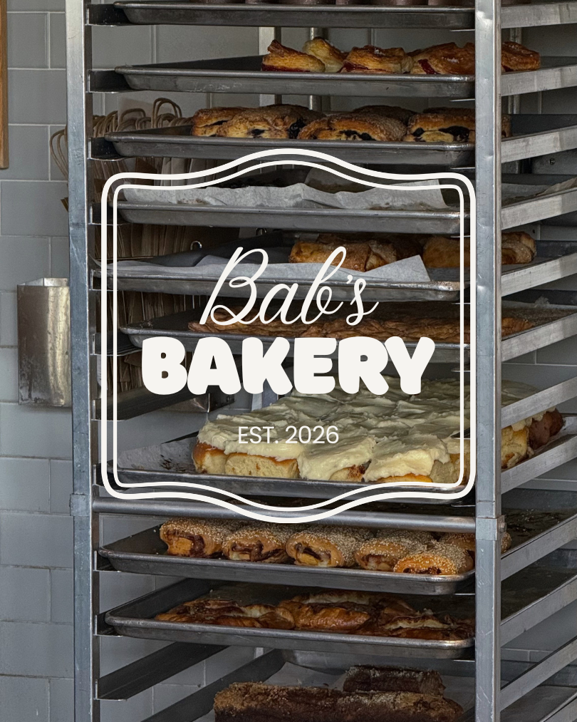 Metal bakery rack filled with various baked goods like cookies, bread, and pastries inside a bakery shop.