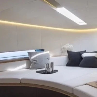 Modern lounge area with a curved white seating arrangement, gray and black cushions, a tray with drinks, in a well-lit room with sleek design.