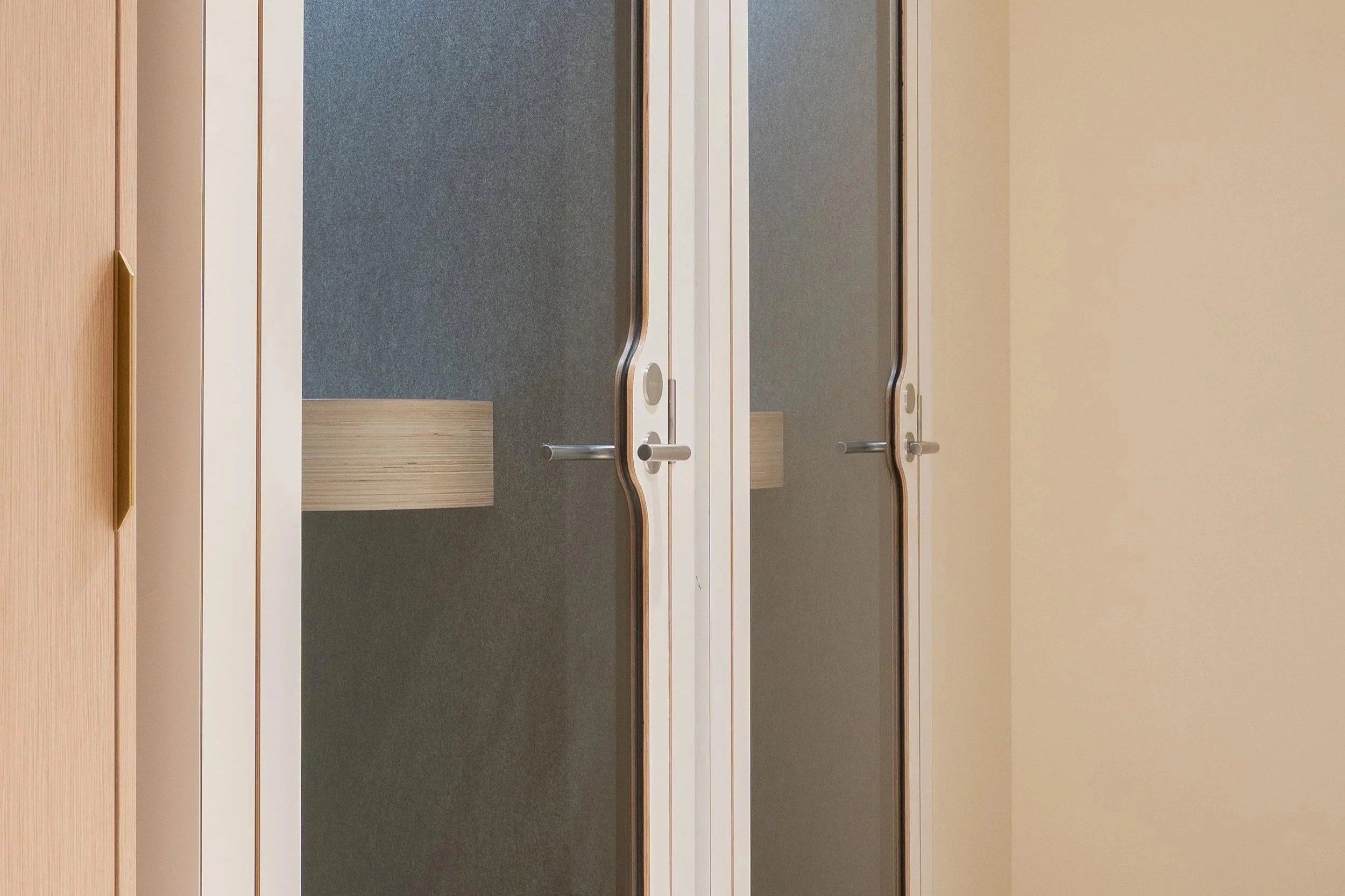 Interior view of a space with wooden and beige walls, featuring sliding glass doors with metal handles.