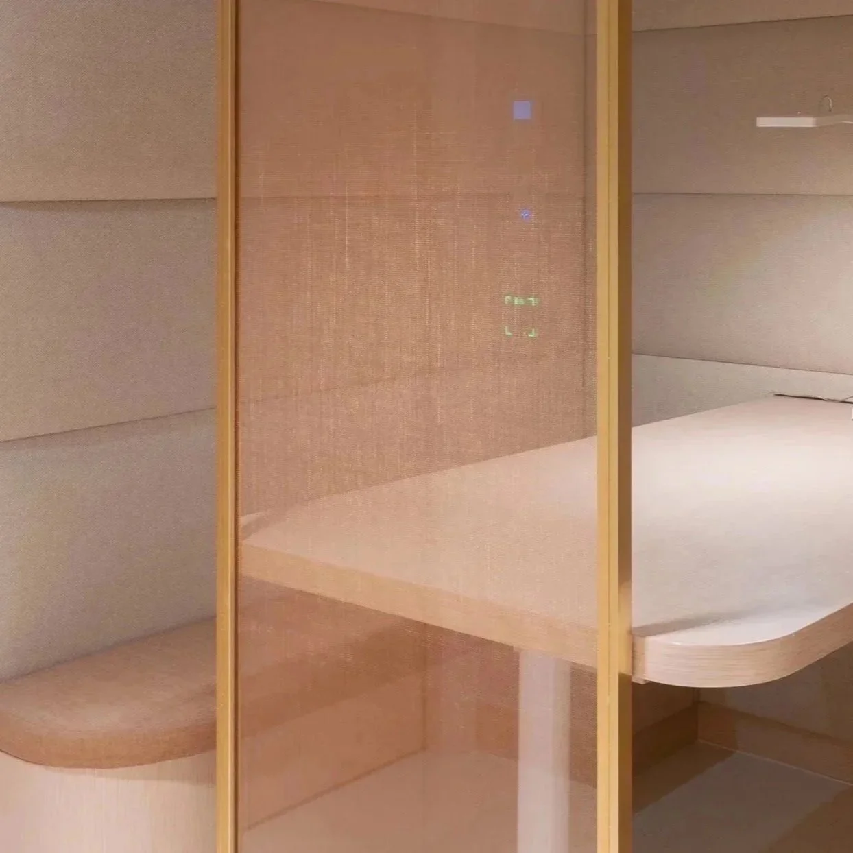 A modern, minimalist bedroom with padded light gray walls, a built-in bed with a curved white mattress, and a wooden privacy screen.