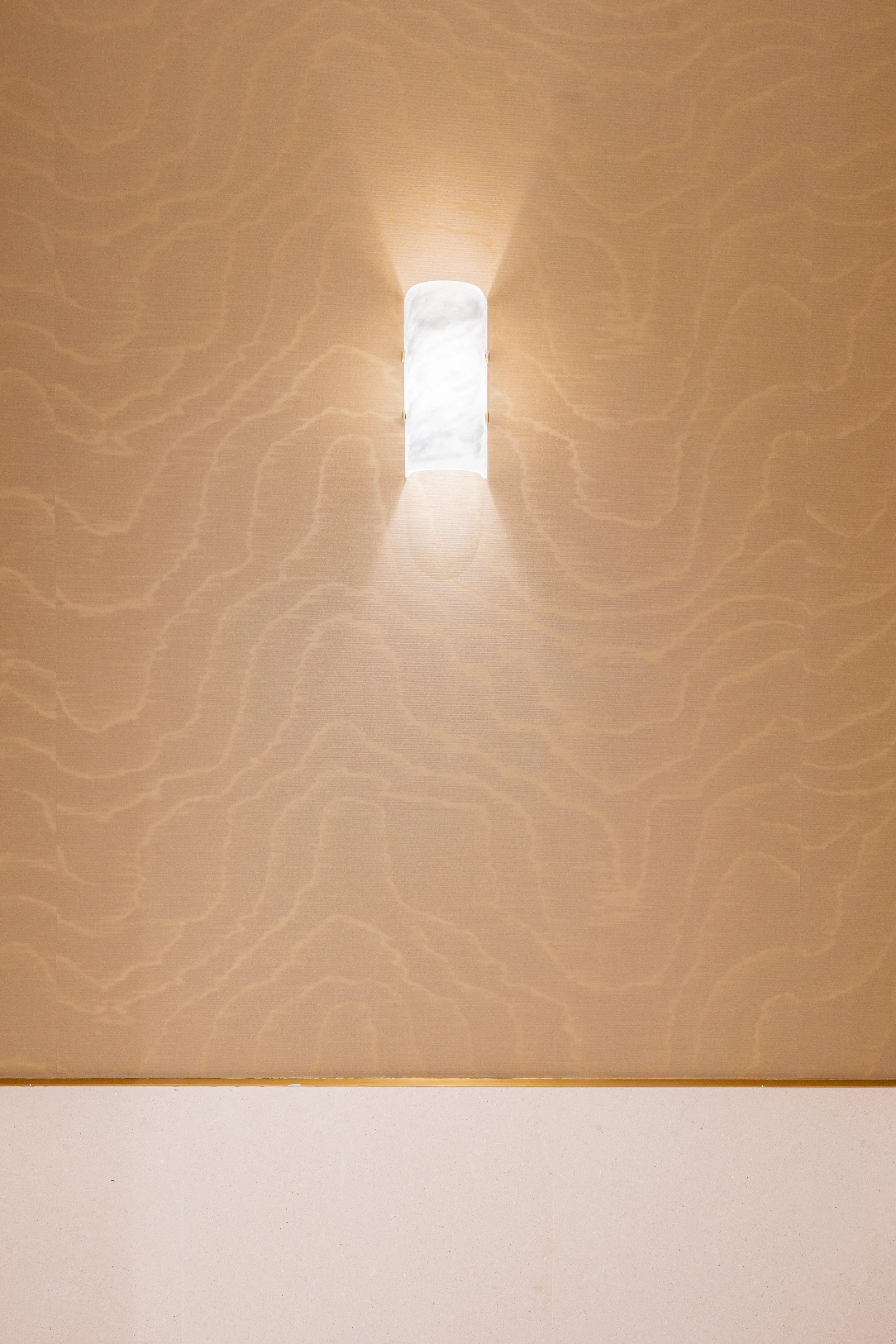 Close-up of a textured wall with a small, rectangular light fixture emitting soft white light.