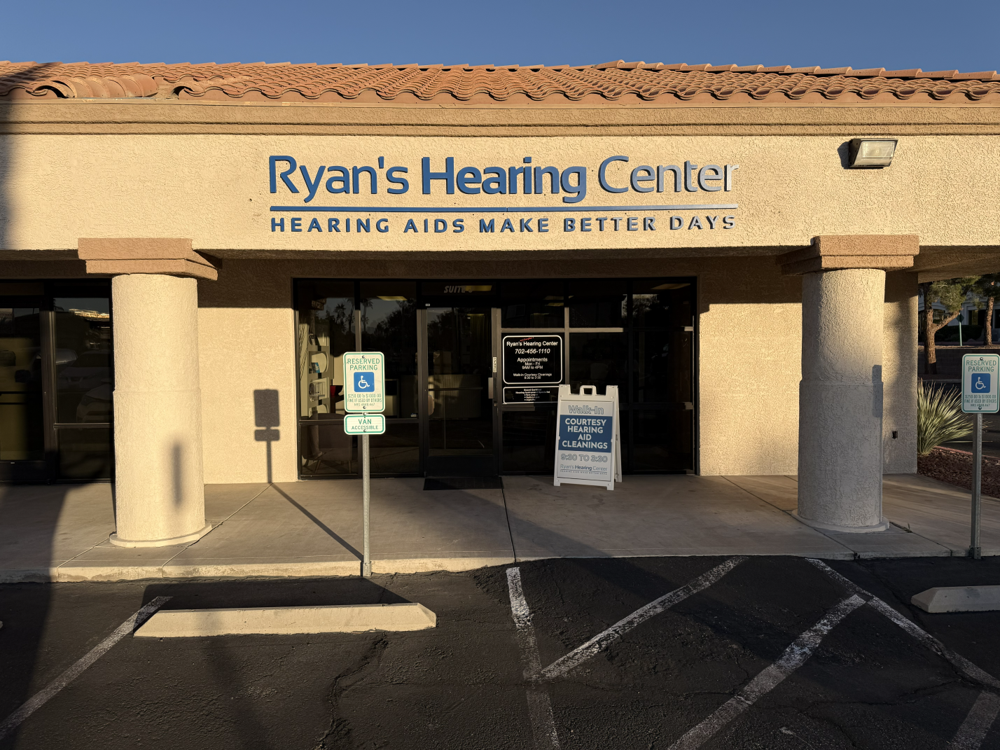 The front of Ryan's Hearing Center with large signage, two reserved parking spots with accessible signs, and a sidewalk leading to the entrance.