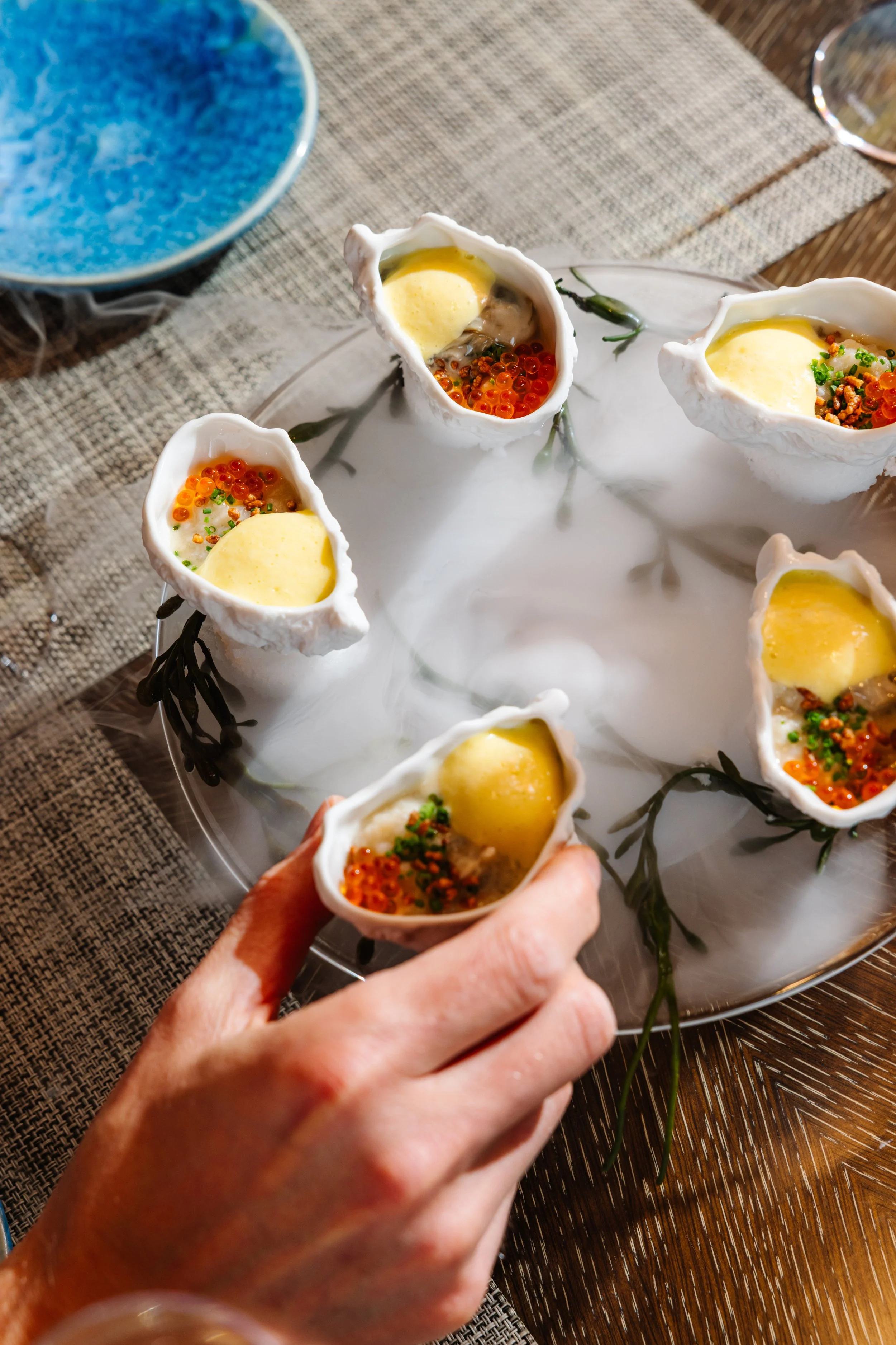 Seafood appetizers served in shell-shaped cups arranged on a decorative plate on a table.