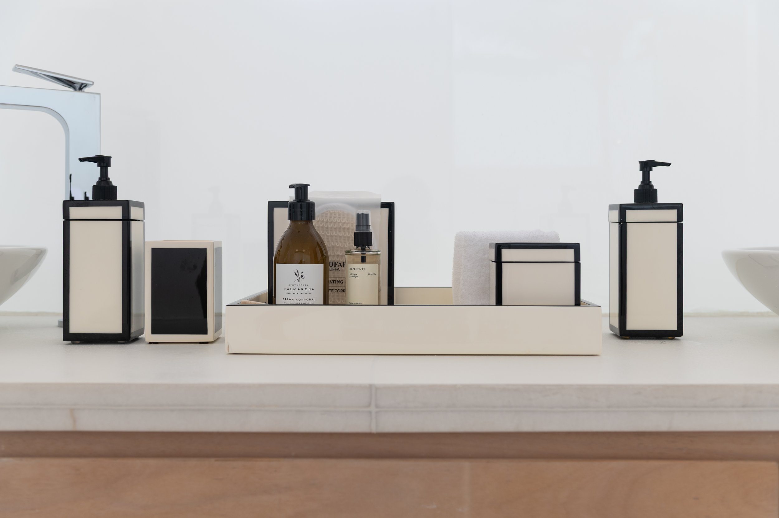 Assorted personal care bottles and containers arranged on a white tray on a bathroom shelf against a white background.