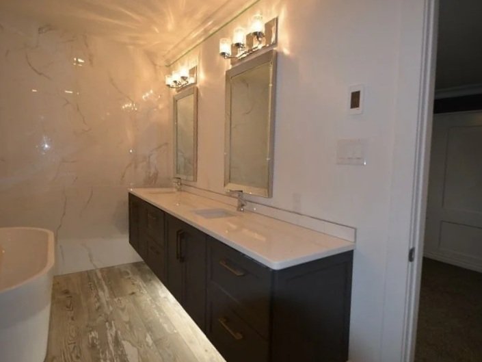 Bathroom with double vanity sinks, mirrored medicine cabinets, and modern lighting fixtures above each mirror.