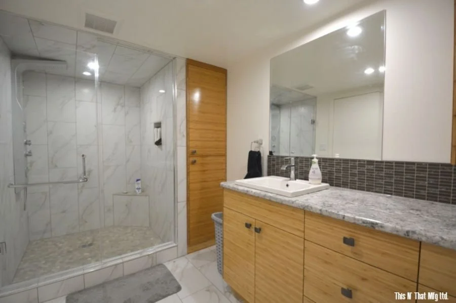 Bathroom with walk-in shower, wooden cabinets, and a large mirror above a granite countertop.