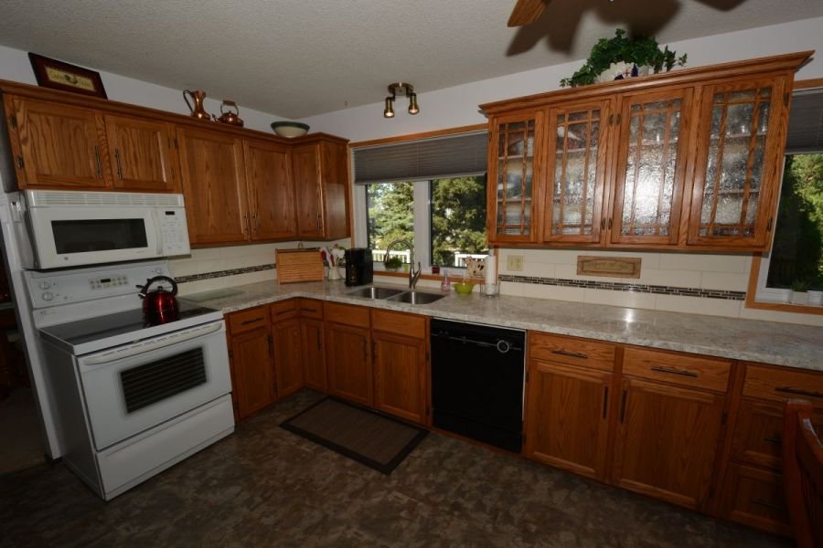 Kitchen with wooden cabinets, white appliances, a window above the sink, and a granite countertop.