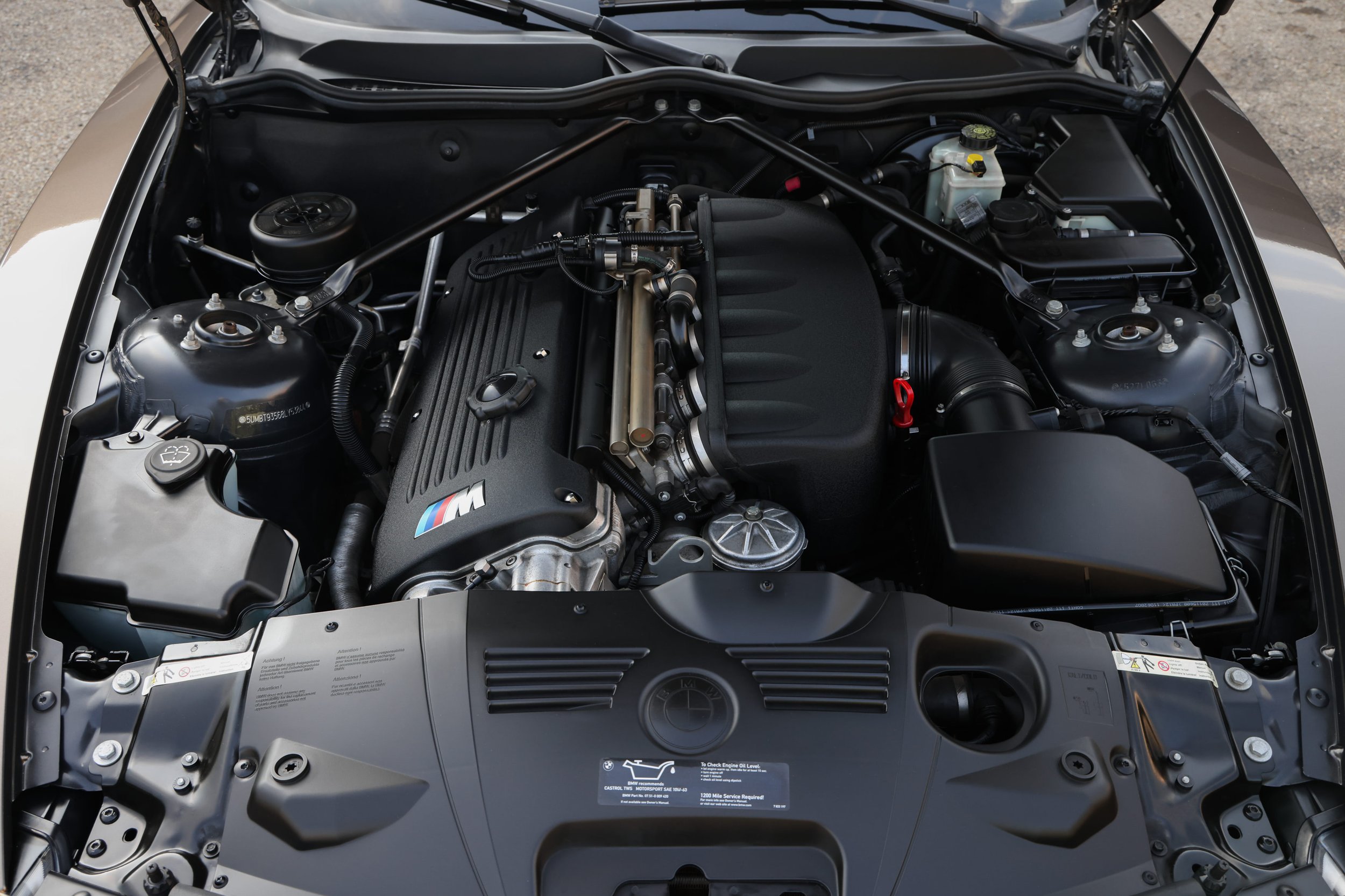 Under the hood of a BMW car, showing the engine and various components.