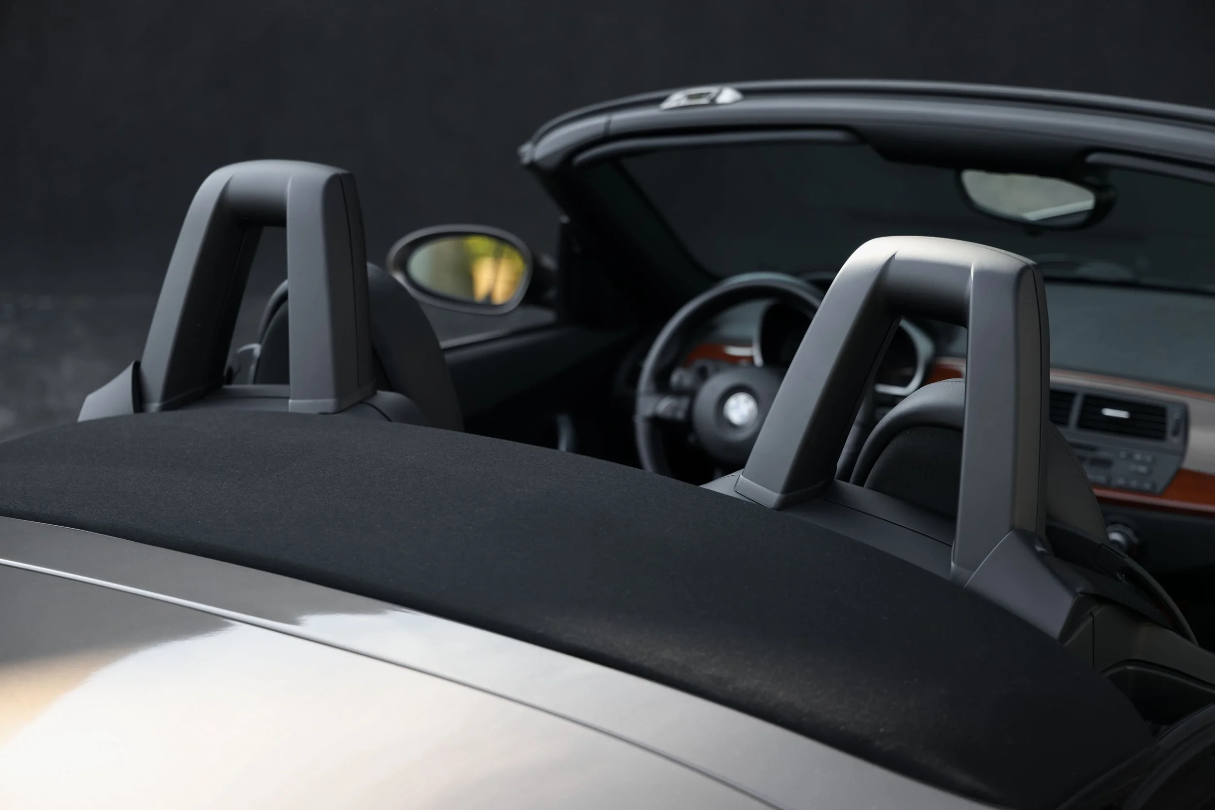 Close-up of an interior view of a convertible car, showing the headrest and part of the dashboard with a dark background.