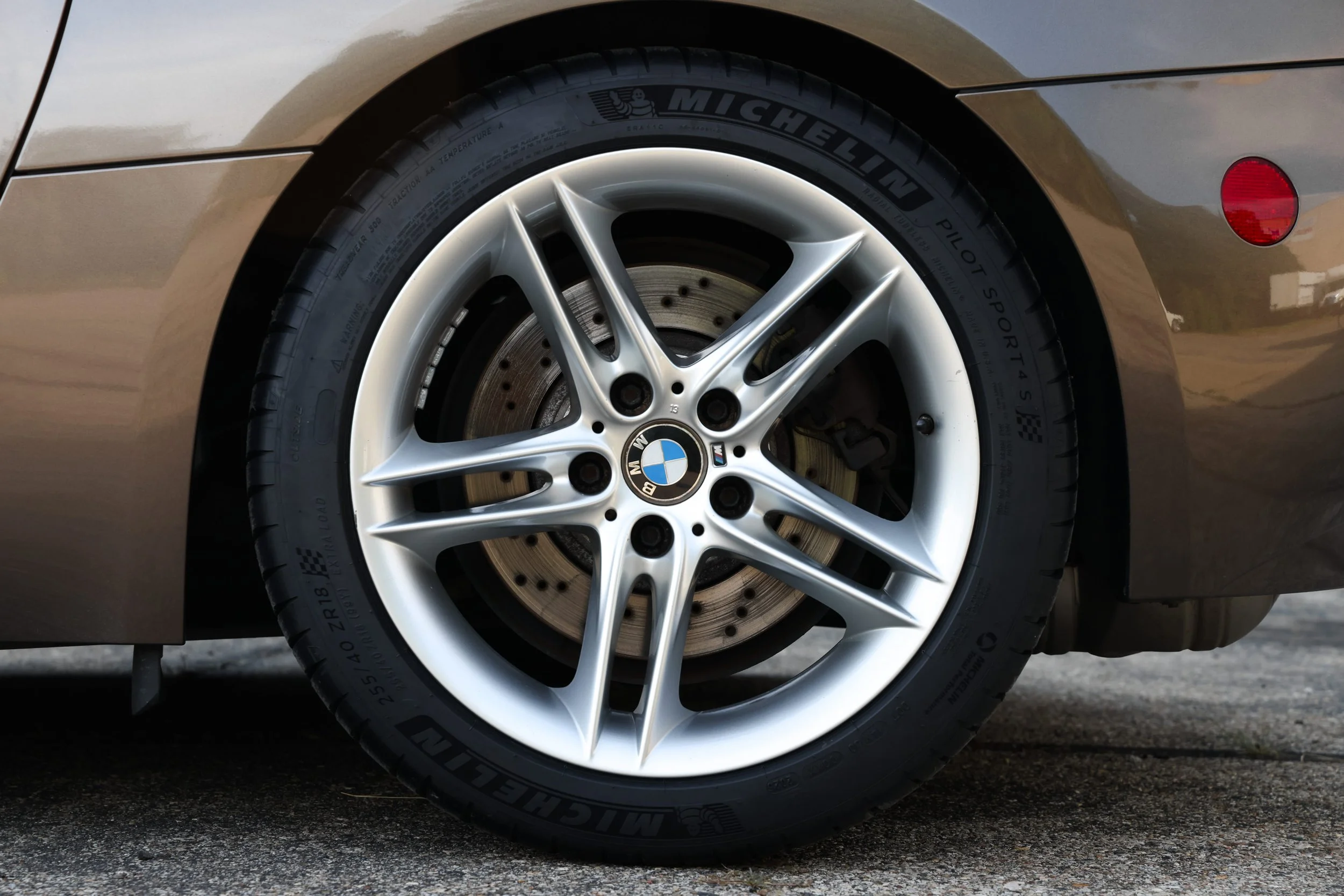 Close-up of a BMW car wheel with a Michelin Pilot Sport 4 S tire, silver alloy rim, and a brake disc visible behind.