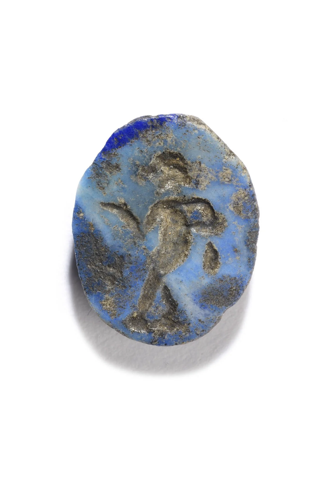 A blue stone with a human figure carved into it. It is a male, standing and facing left. His right arm is outstretched and left arm bent.
