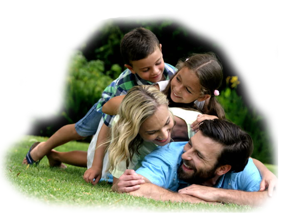 A family of four, including two children, lying on the grass and playing together outdoors.