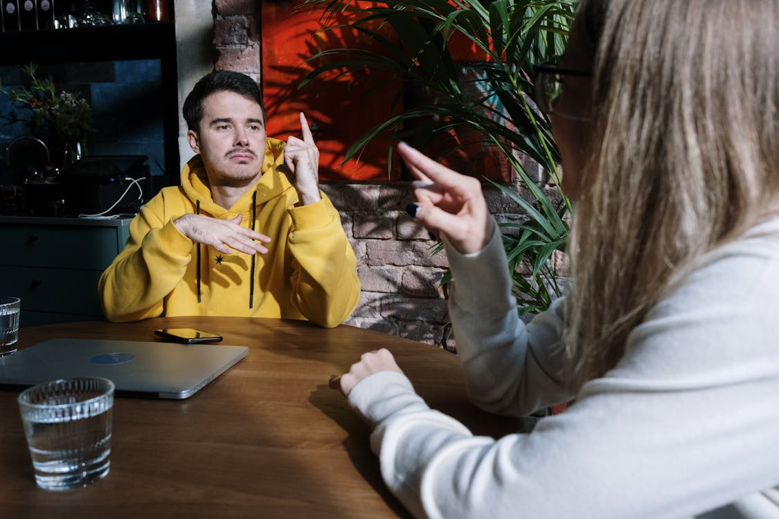 Two people signing to each other at a table