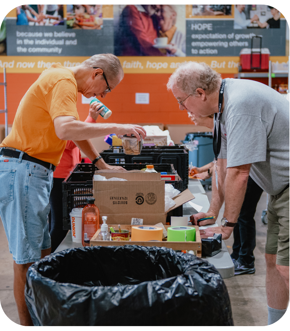 Volunteers looking at orders on a table ensuring and marking that every item is there.