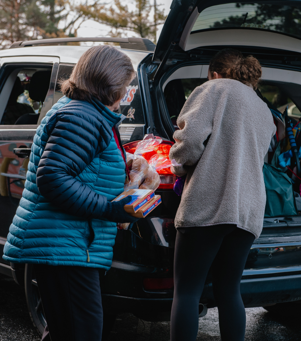 2 volunteers loading groceries into a minivan's trunk.