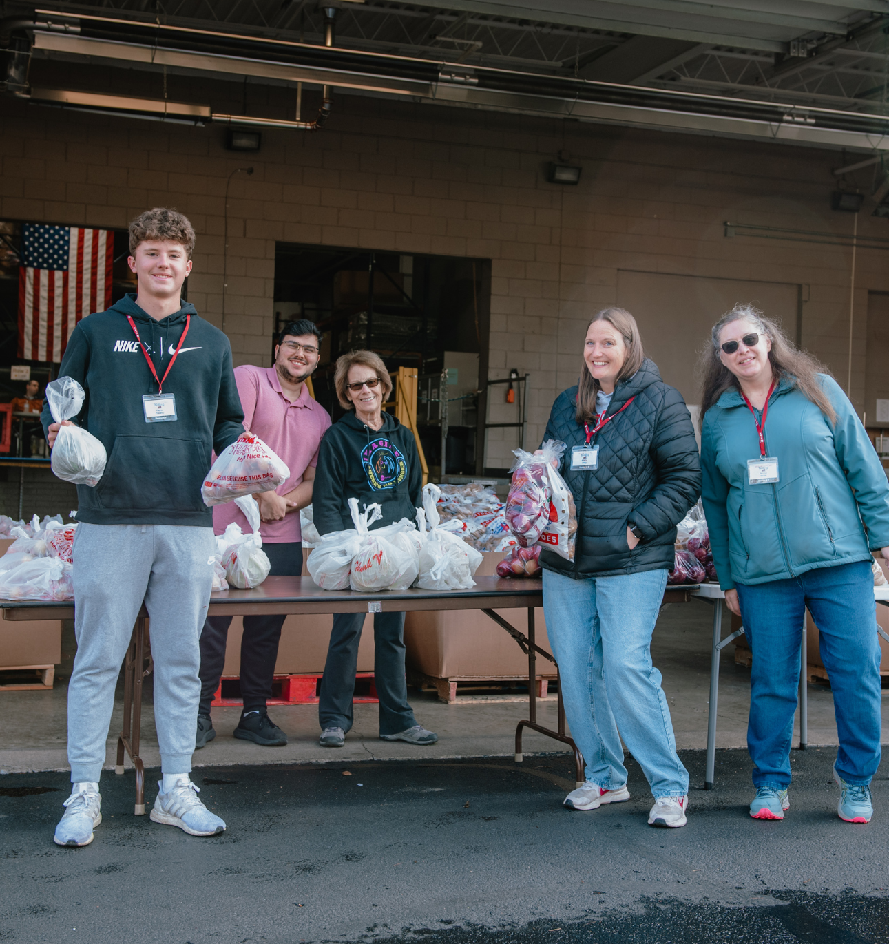 A group of volunteers posing and smiling with produce they are giving to clients at Thanksgiving Blessing.