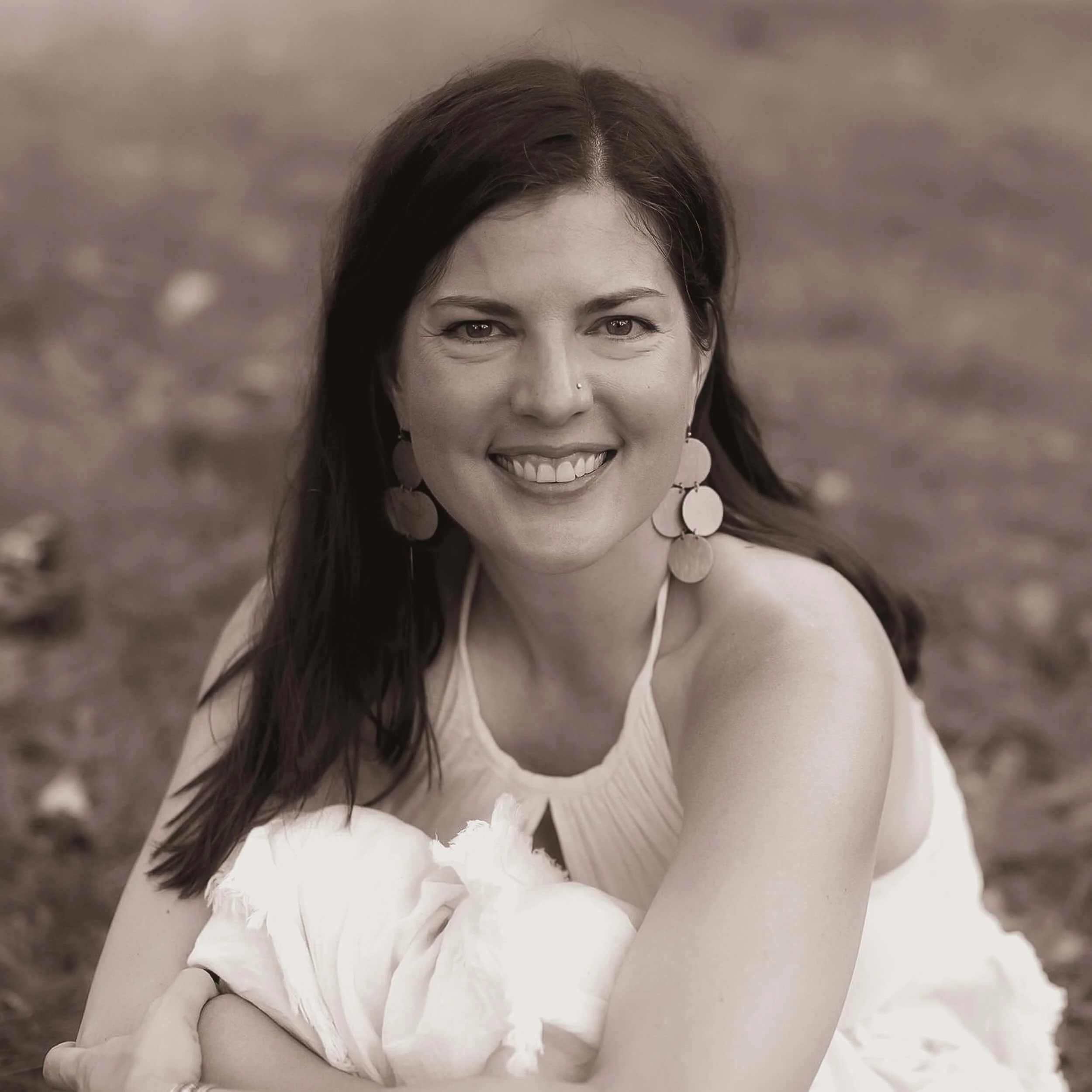 Kristi Amdahl sitting in the grass and smiling at the camera