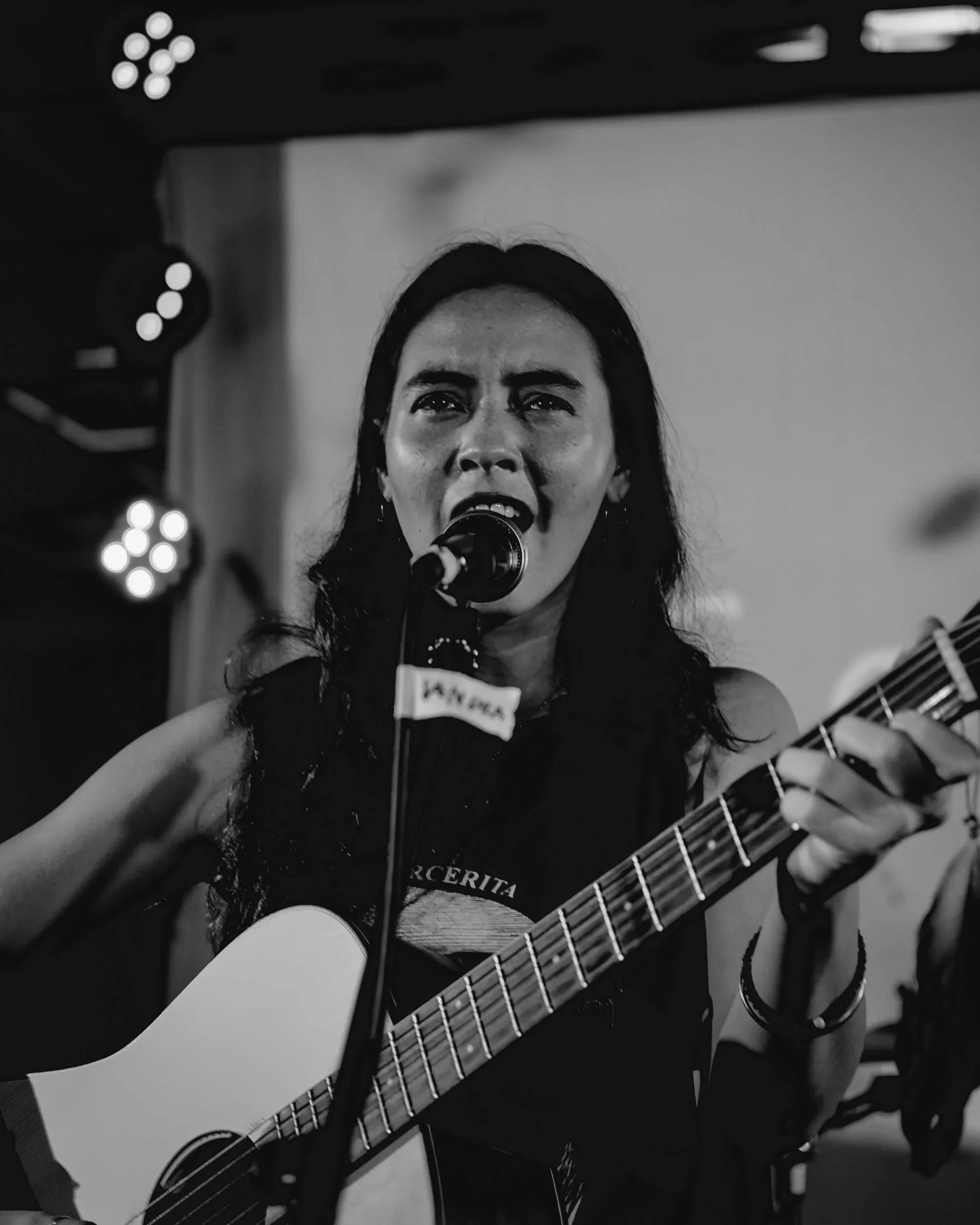 woman playing the guitar and singing into a mic
