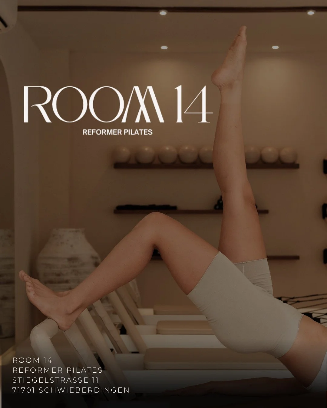 Ein Fitnessraum mit einem personifizierten Reformer Pilates-Absatz, der auf der Seite liegt, in einem Pilates Raum mit beige Wandfarben, Regalen und dekorativen Gegenständen, Text über Raum 14 Reformer Pilates, Adresse in Schwieberdingen.